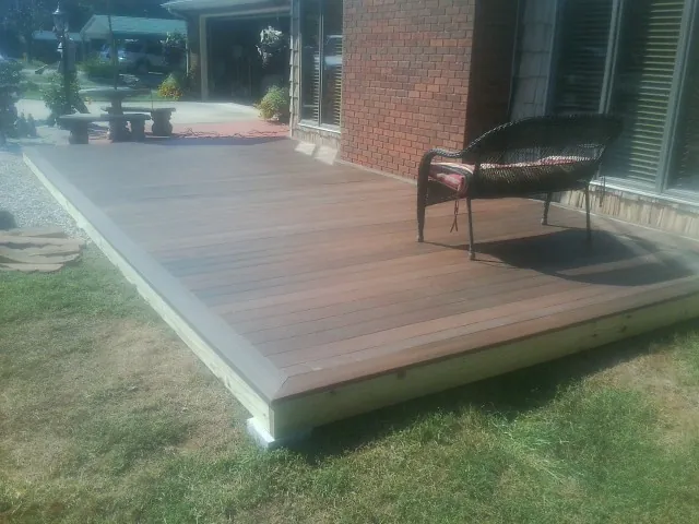 New wood deck and wicker chair beside a brick house in Telford
