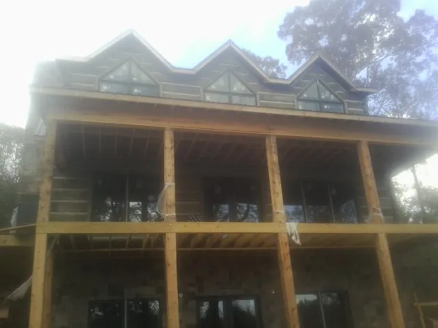 Dormers and porch framing on a large log home under construction — Roof Coating work by our crew in Telford