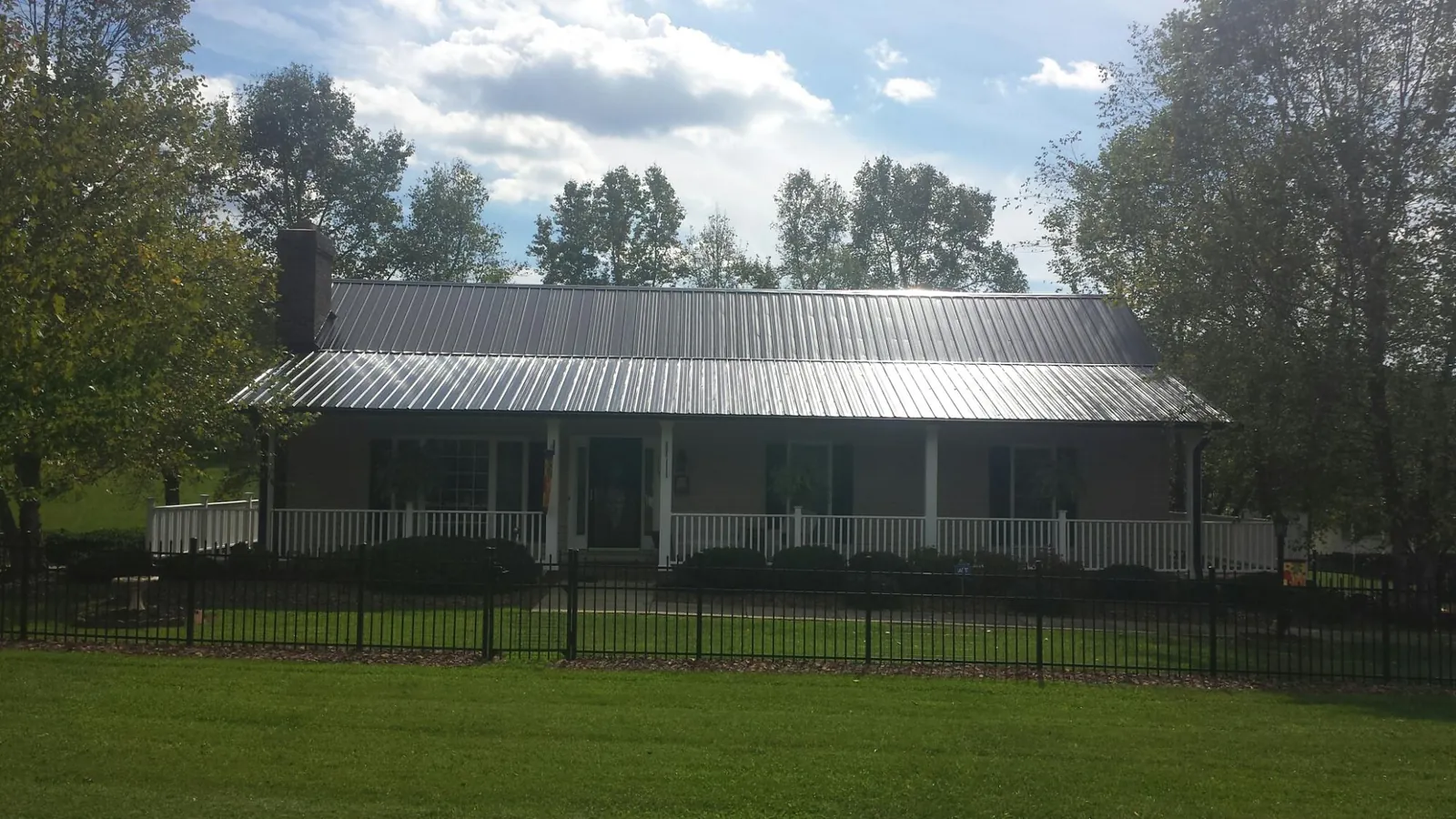 Gray metal roof on a brick ranch with a full width front porch — Gutter Guard Installation work by our crew in Telford